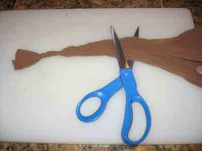 Tie a knot in the pantyhose and cut several inches away from the knot.