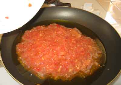 Adding tomatoes for the greek recipe strapatsada.